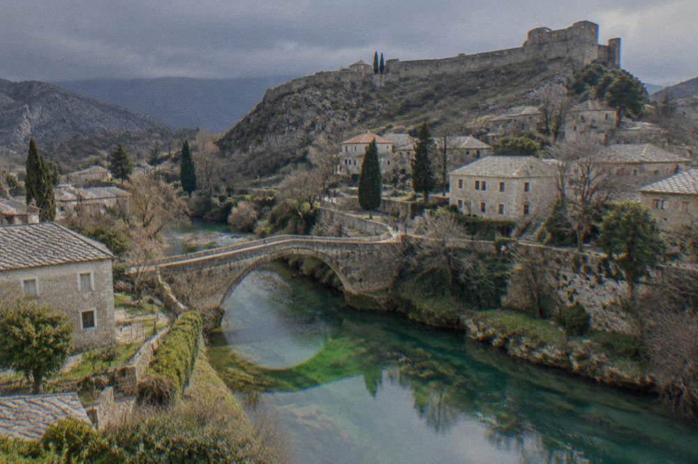The Bregava river flowing under an old stone bridge with green banks