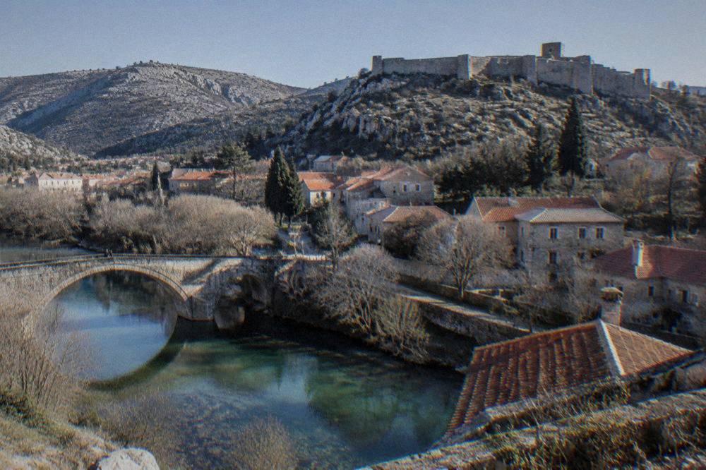 View over red roofs of Stolac with the hilltop fortress in the background