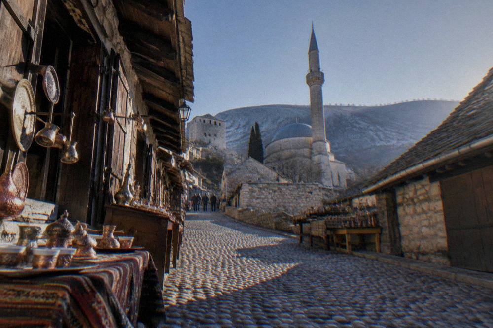 A walled old town with stone buildings and a clock tower under a clear sky