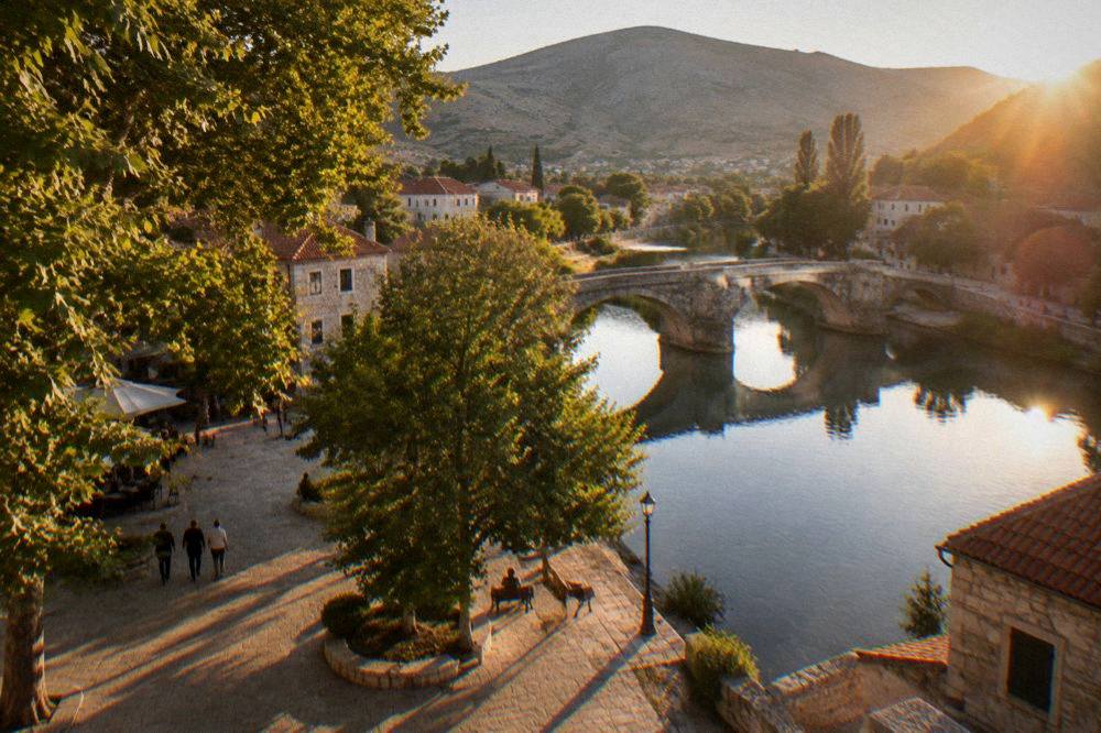 An old stone bridge reflected in still river water at golden hour