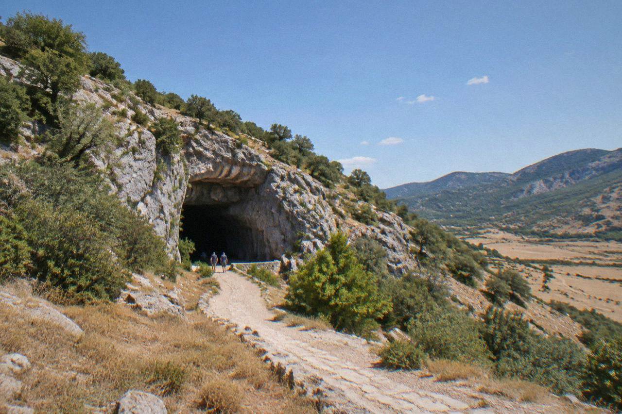 The entrance of Vjetrenica cave set into a rocky hillside above the dry plain of Popovo polje