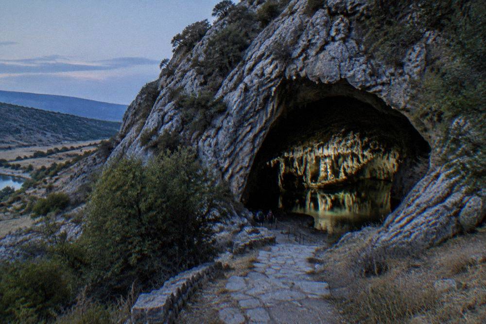 A still underground lake inside the cave reflecting limestone formations under electric light
