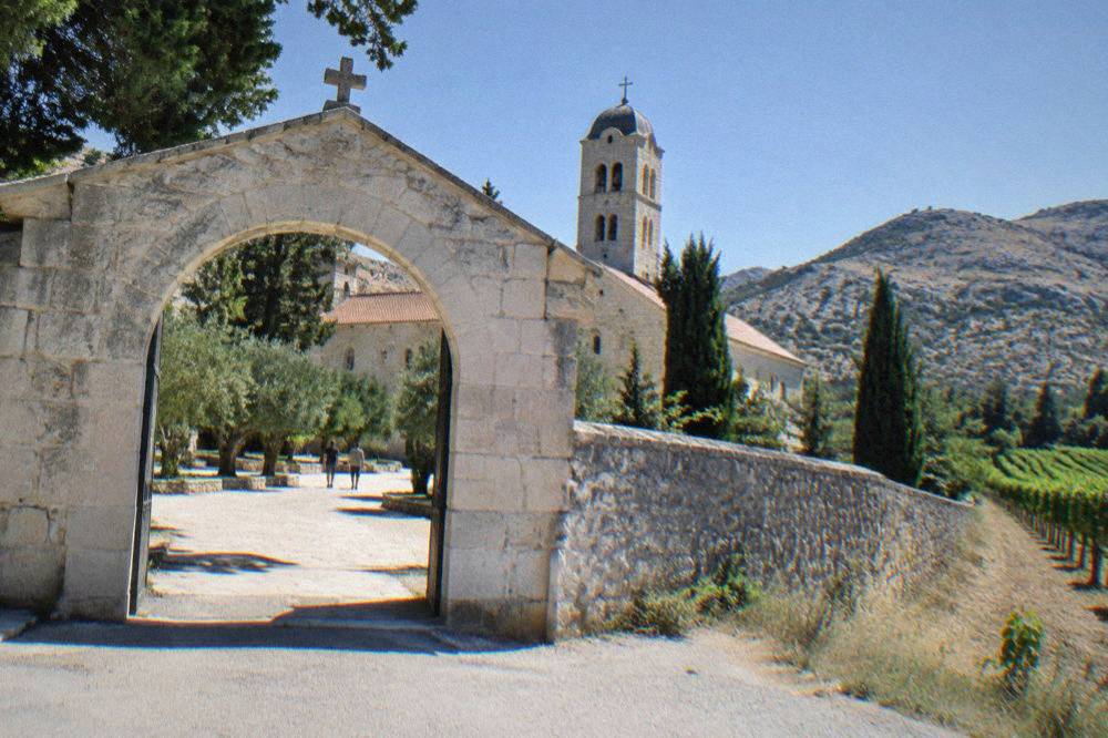 The arched entrance gate of a monastery compound built from pale limestone blocks