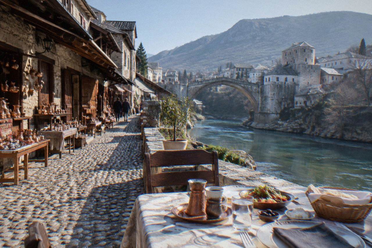 Table set for a meal on a stone terrace beside the Neretva river in Mostar