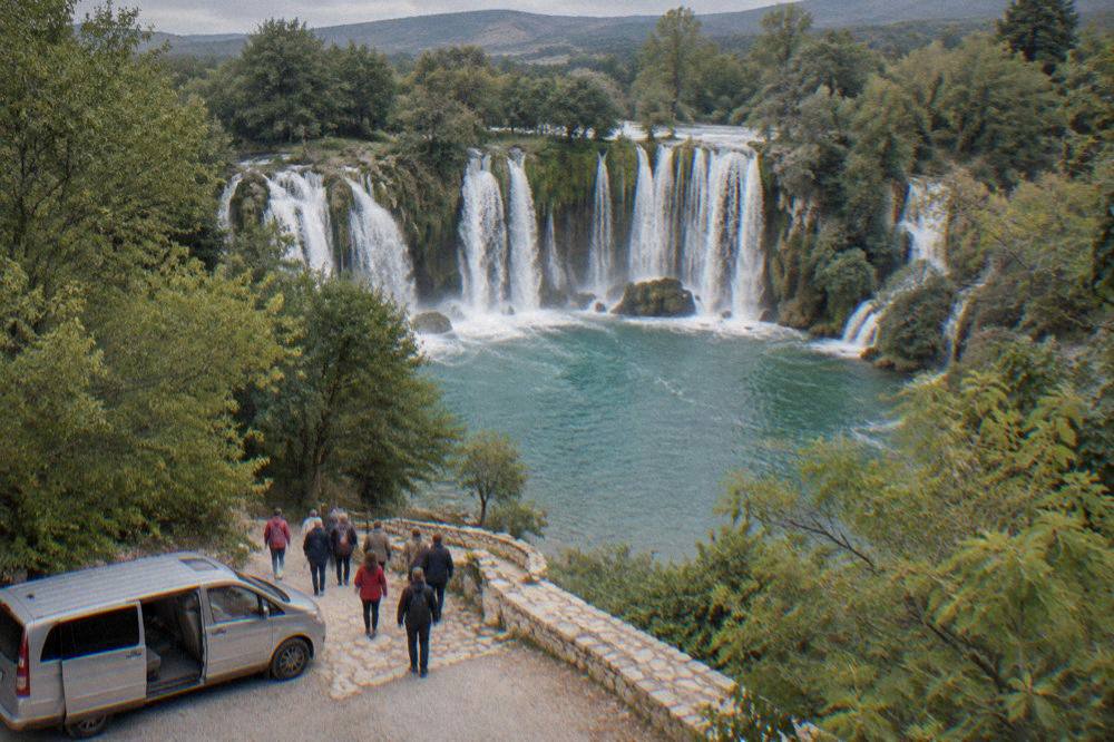 A minivan tour group arriving at the Kravica waterfall in the late afternoon