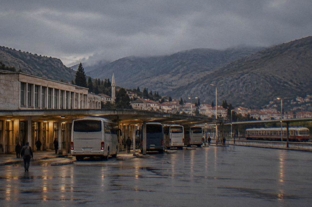 An intercity coach parked at a small bus station platform in the evening