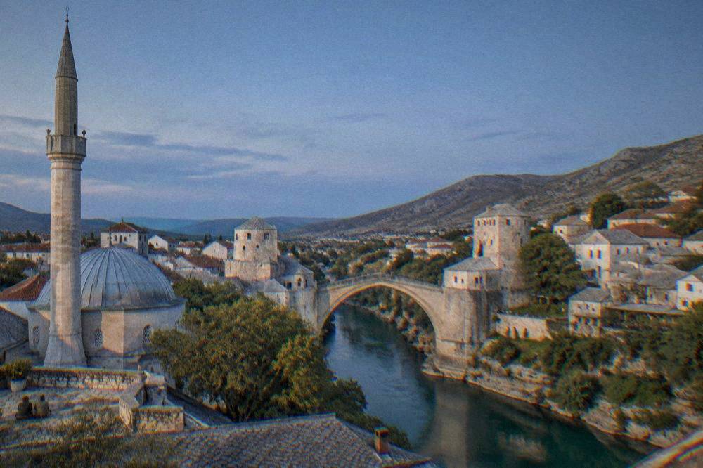 The Old Bridge seen from a raised mosque terrace with the minaret shadow and Old Town rooftops