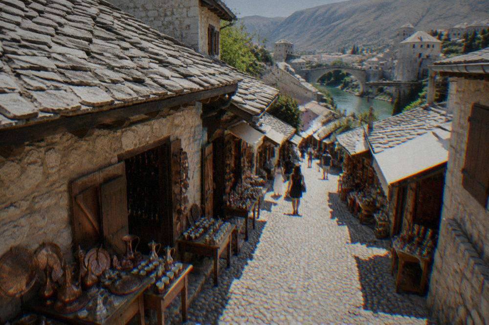 A narrow cobbled street in Kujundžiluk with old stone shopfronts in Mostar
