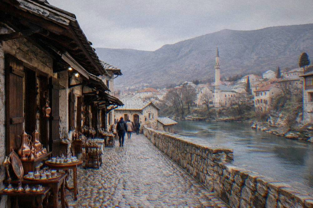 A stone minaret and old rooftops of Mostar old town seen from across the Neretva