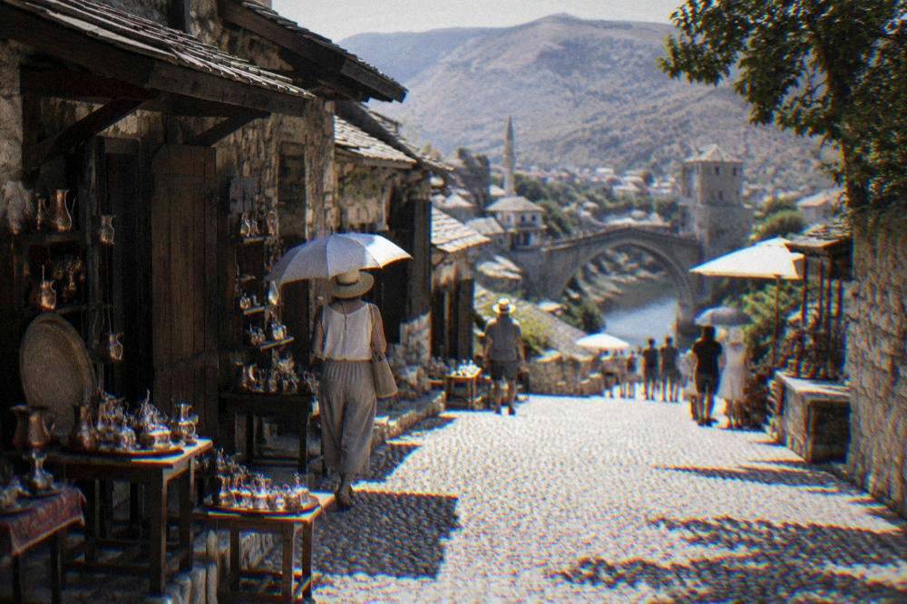 People shading themselves under umbrellas on the stone streets of Mostar's Old Town in summer