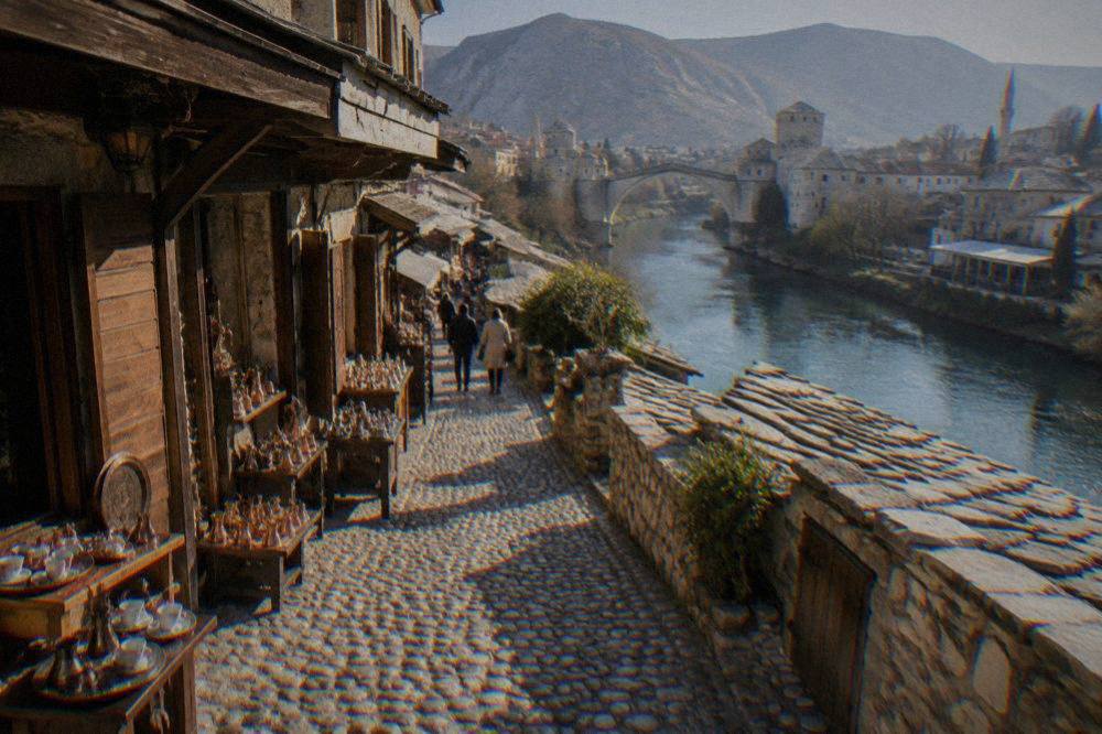 Green Neretva water flowing past stone embankments and riverside buildings in Mostar