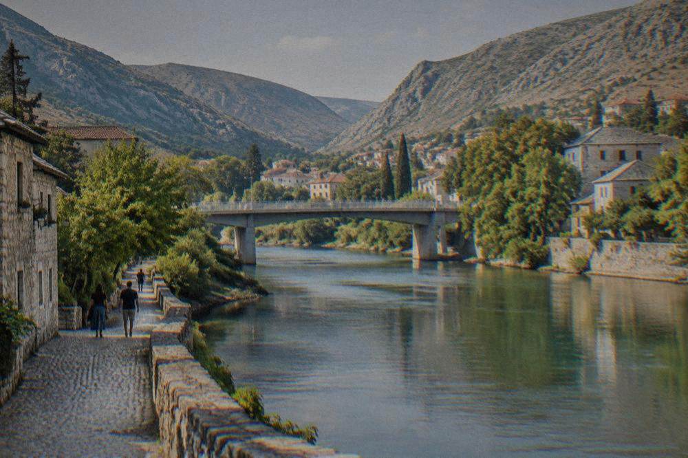 Cobblestone riverside path beside the Neretva with old stone buildings