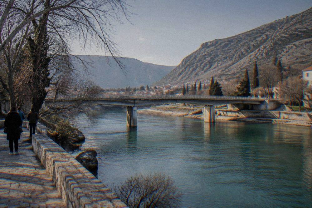 Sunlight on a wide green river flowing between dry hills