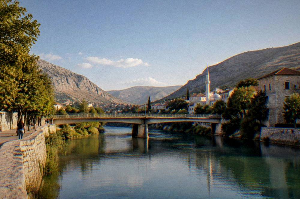 Evening light on a stone bridge and calm river in a valley town