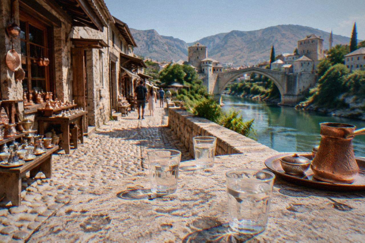 Small glasses of clear rakija on a stone table beside the Neretva river in Mostar
