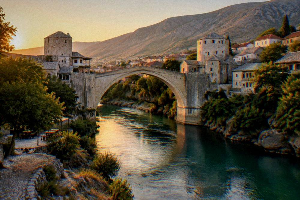 Evening light on the Neretva river and the Old Bridge in Mostar seen from the riverbank