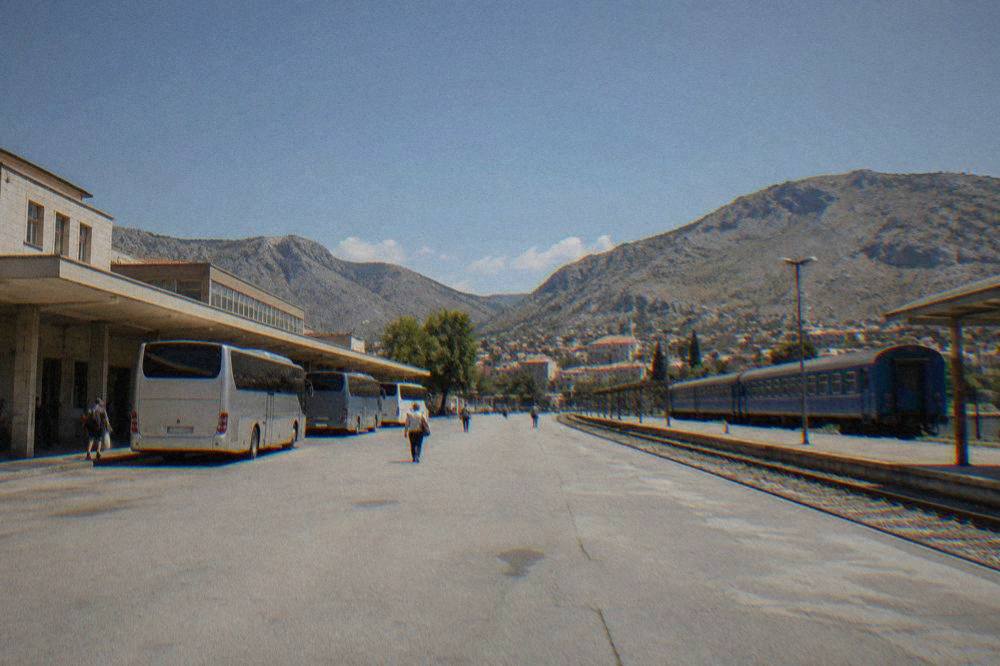 The platform of a railway station in Bosnia and Herzegovina with a blue passenger train waiting