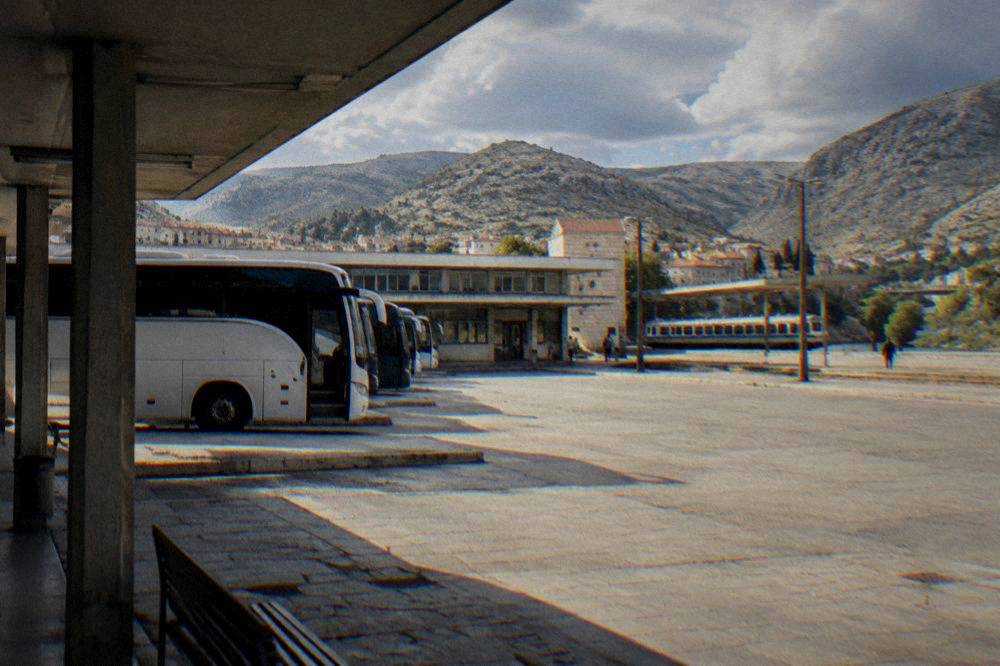 A long-distance coach parked at a bus station in a Balkan city