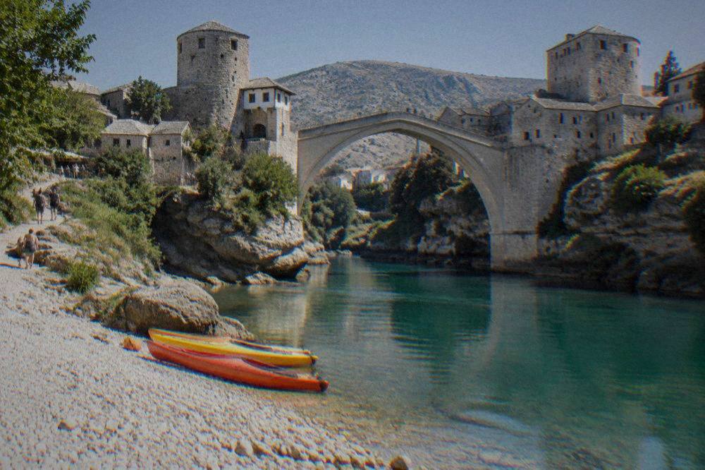 Kayaks resting on a pebble bank beside clear green river water