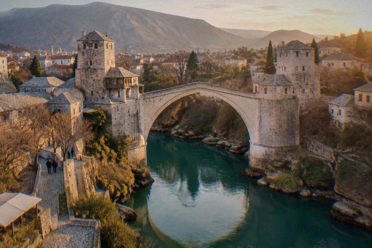 The stone arch of the Old Bridge in Mostar spanning the green Neretva river at golden hour
