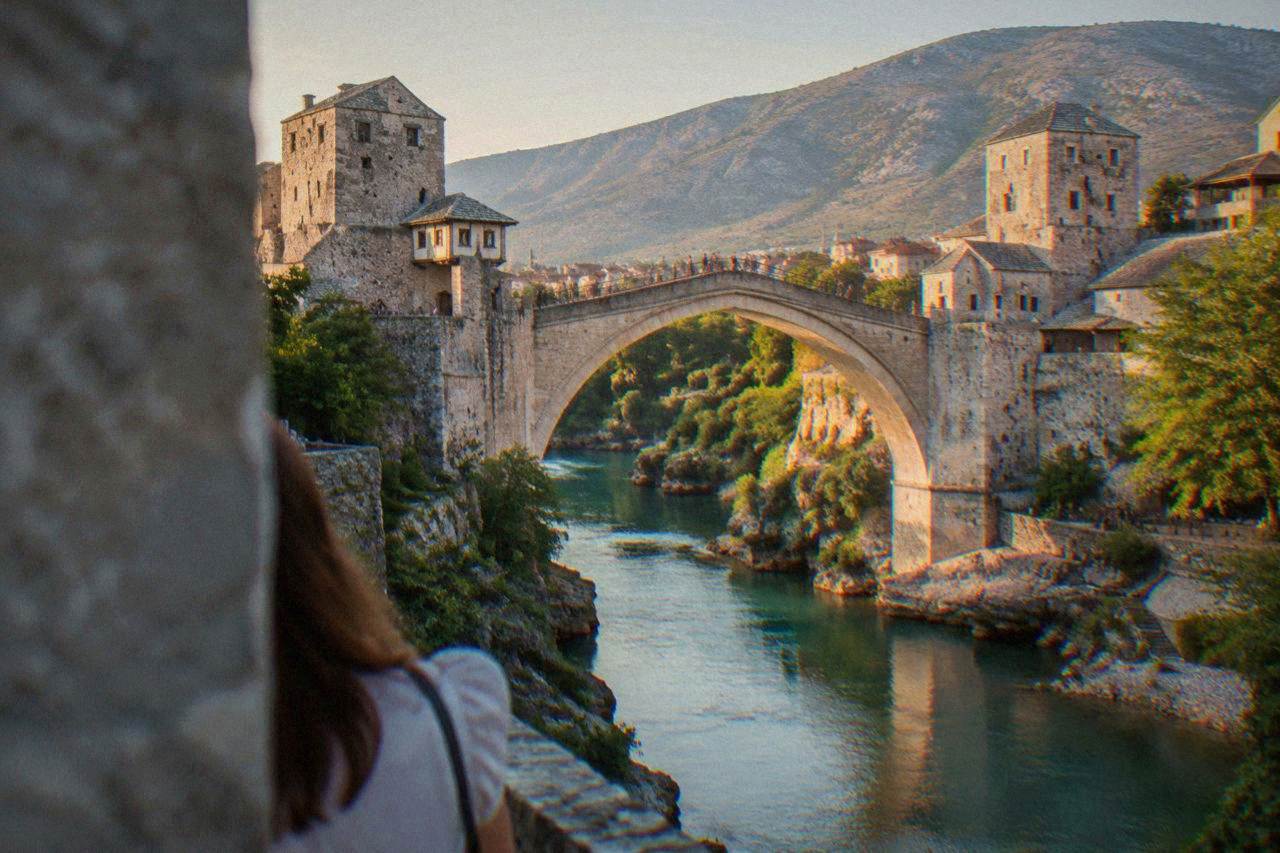 The stone arch of the Old Bridge in Mostar spanning the green Neretva river at golden hour