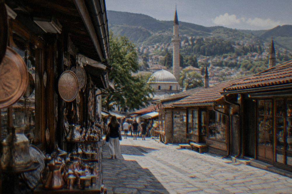 Red-tiled roofs of Sarajevo old town with minarets and green hills behind