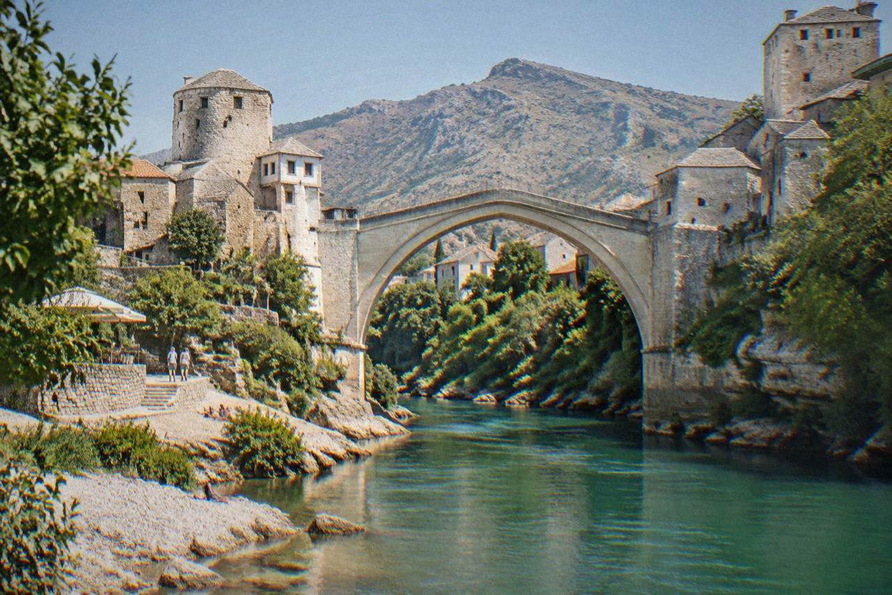 The stone arch of the Old Bridge in Mostar seen from the Neretva riverbank