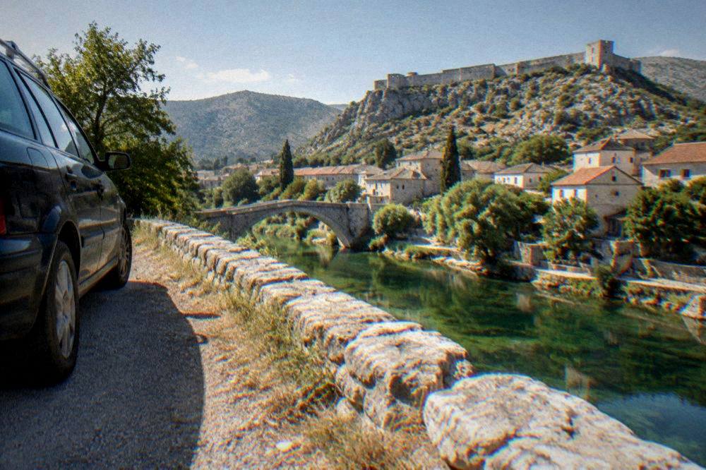 A car parked at a roadside viewpoint above a river valley in Herzegovina