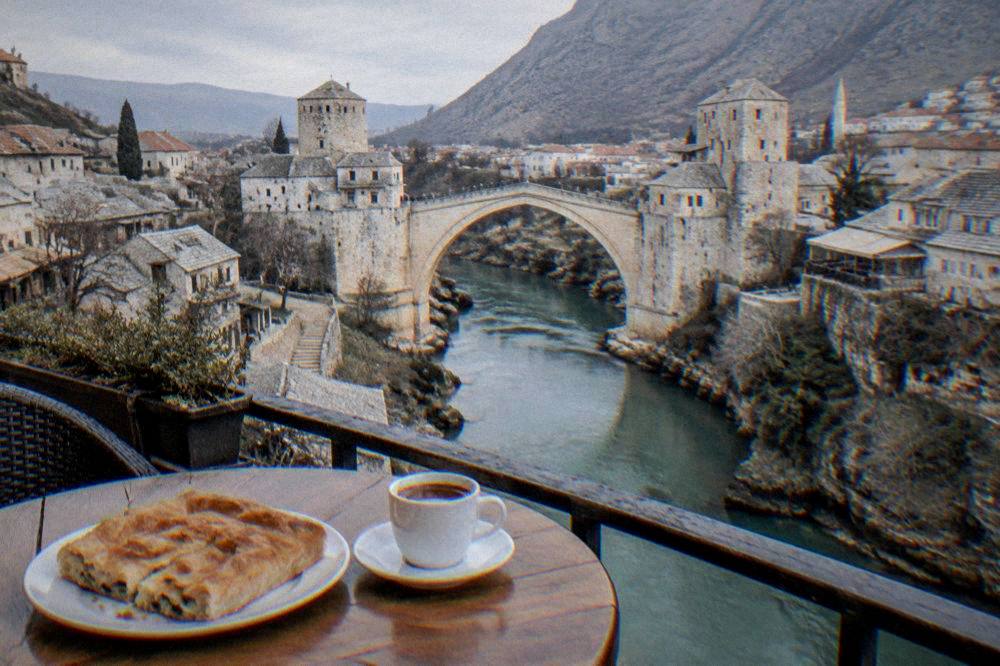 A plate of Bosnian burek pastry and a small cup of coffee on a café table