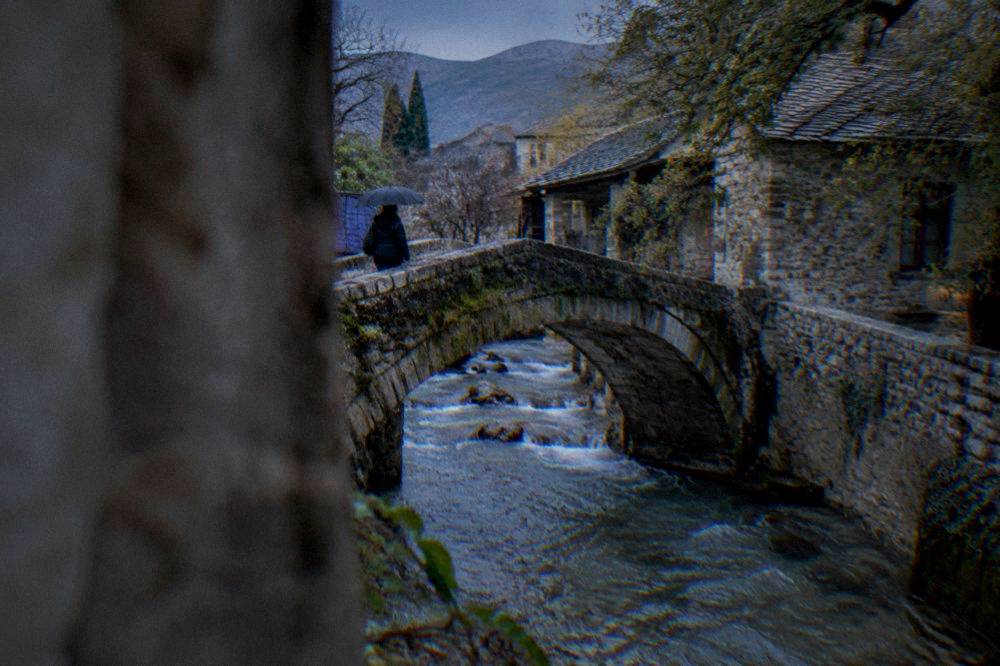 The small stone Crooked Bridge over a fast stream in Mostar in wet weather