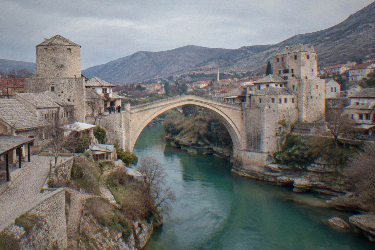 The Old Bridge arching over the green Neretva river at morning in Mostar
