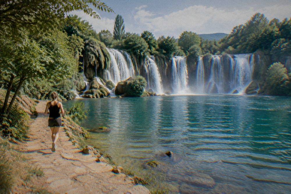 Wide travertine cascade of Kravica waterfall curving around a swimmable pool