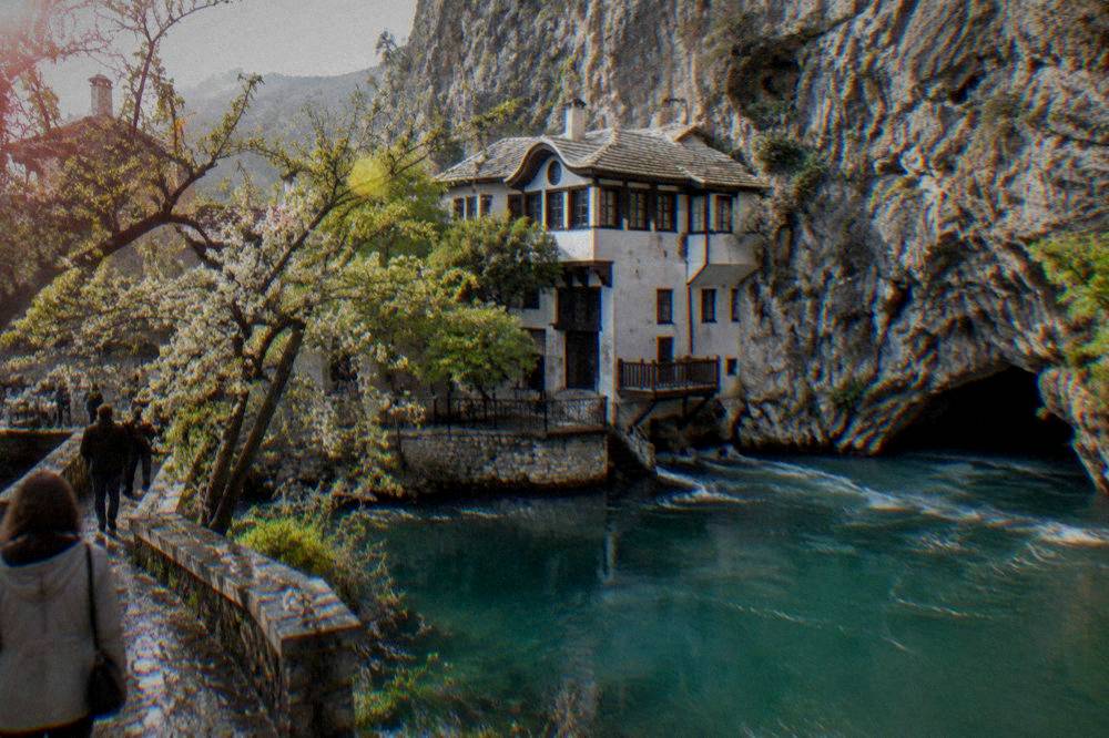 A Dervish lodge built into a cliff face beside a turquoise river spring at Blagaj