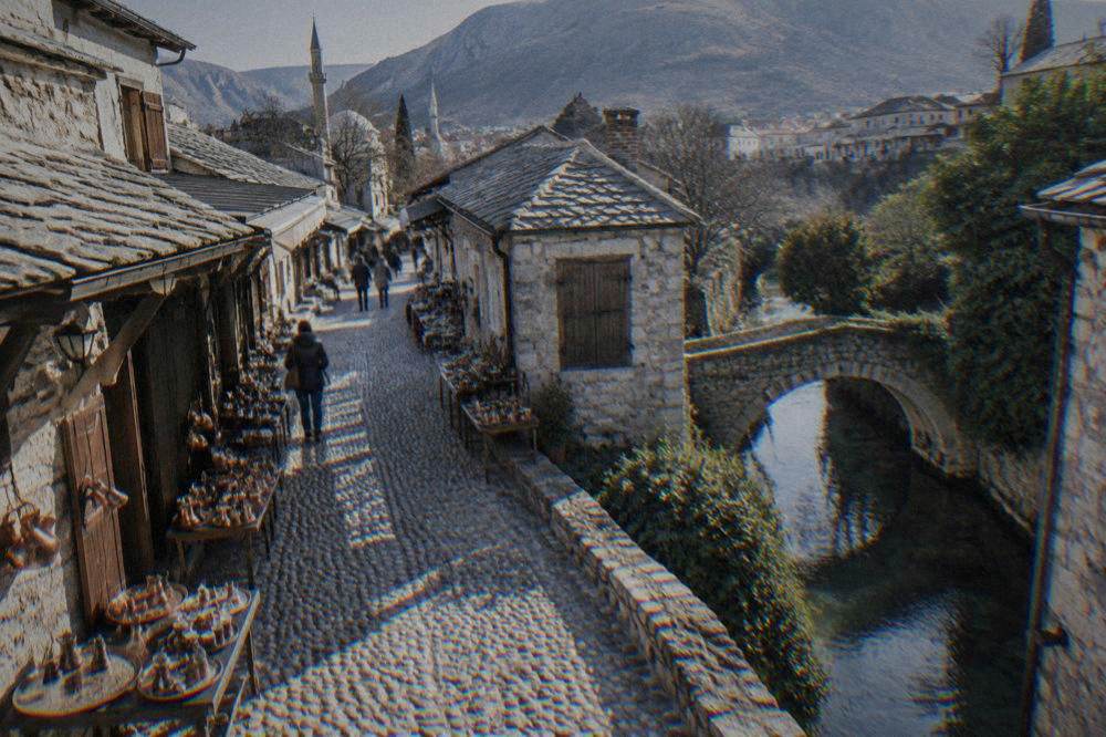 A stone bridge with a small arch over a quiet side stream bordered by greenery